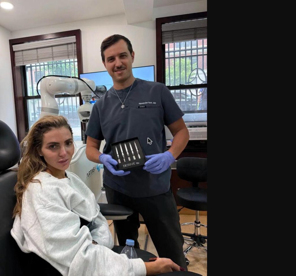 Dr. Alexander Roth, MD holding the AMP Biologics DERIVE exosome kit beside the ARTAS iX robotic system at New York Hair Transplant